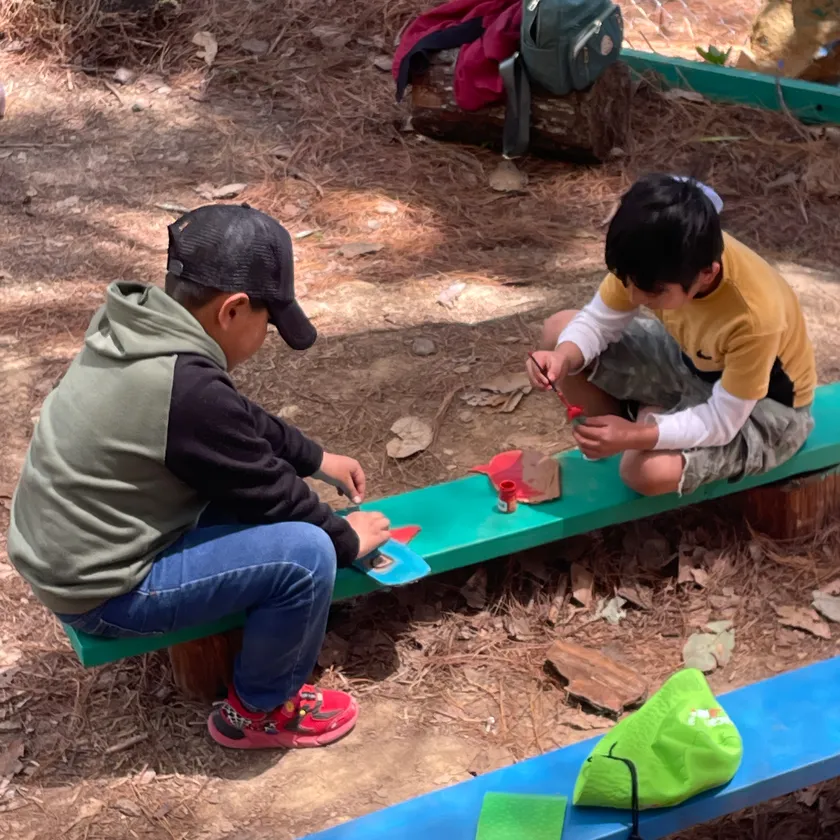 Dos niños construyen juntos sobre una banca al aire libre