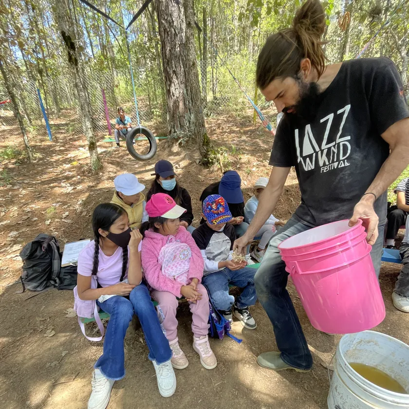 Un facilitador comparte una actividad con niñas y niños en el bosque