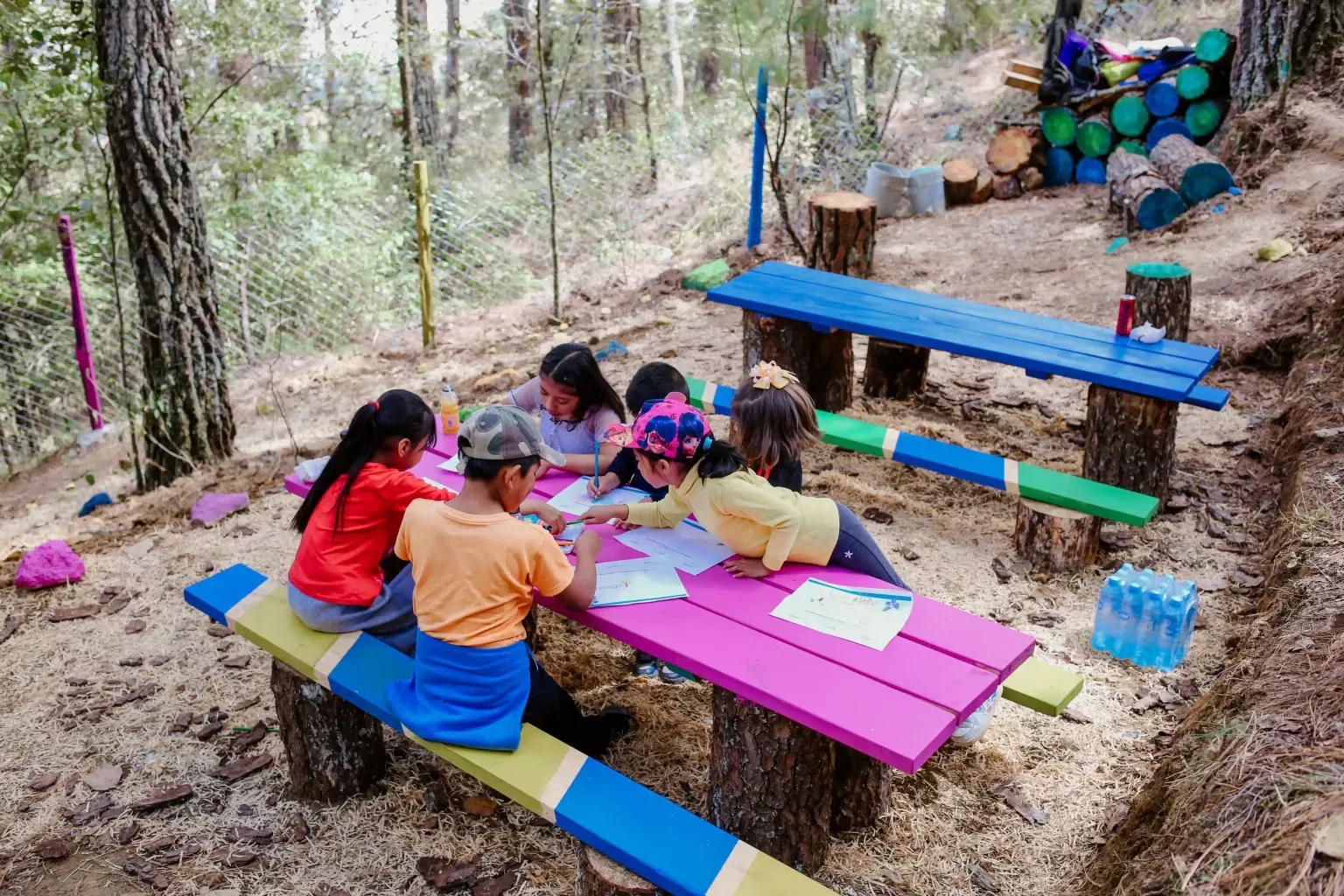 Niñas y niños dibujando en las mesas de colores del espacio