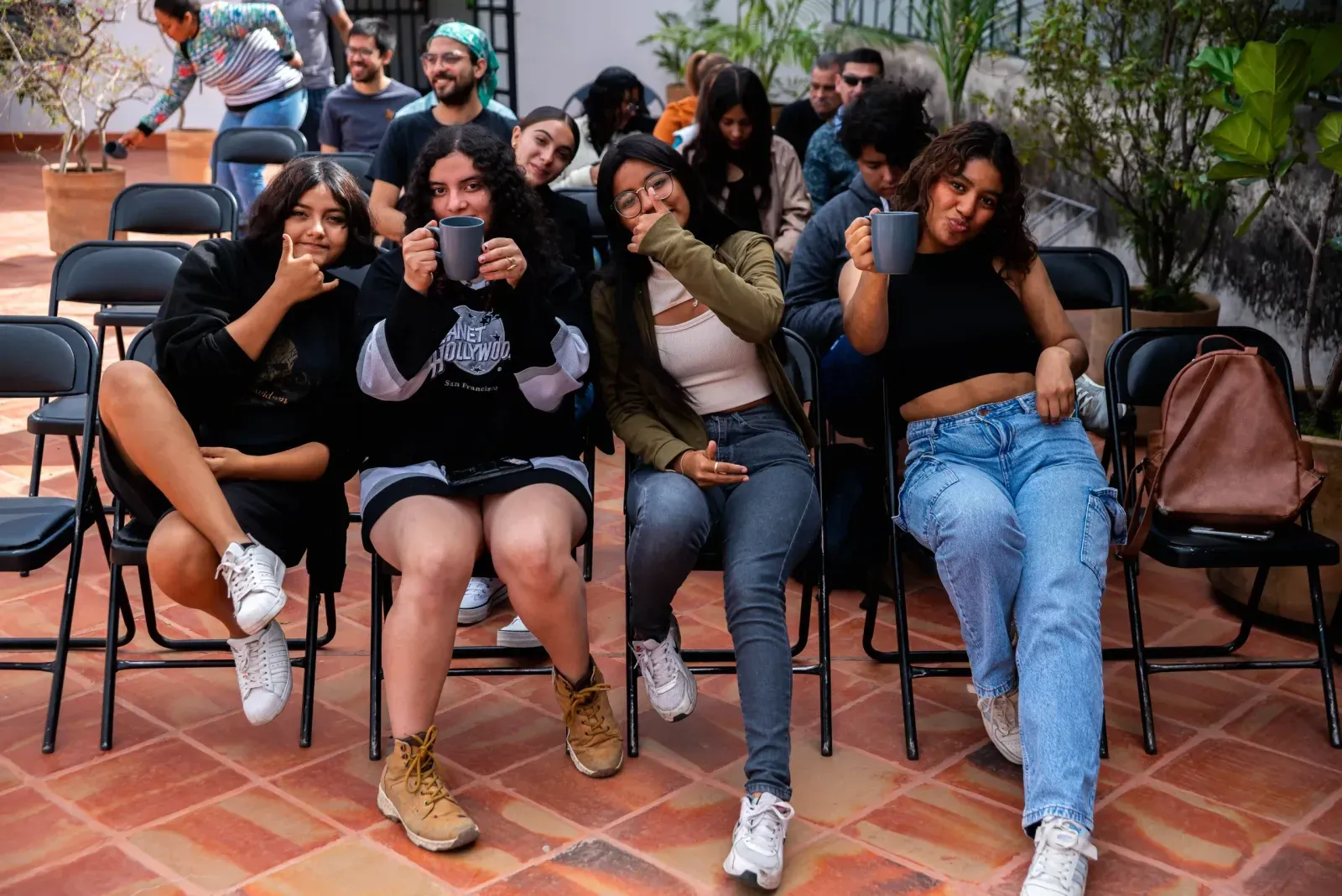 Estudiantes sentadas en sillas escuchan atentas durante un taller al aire libre