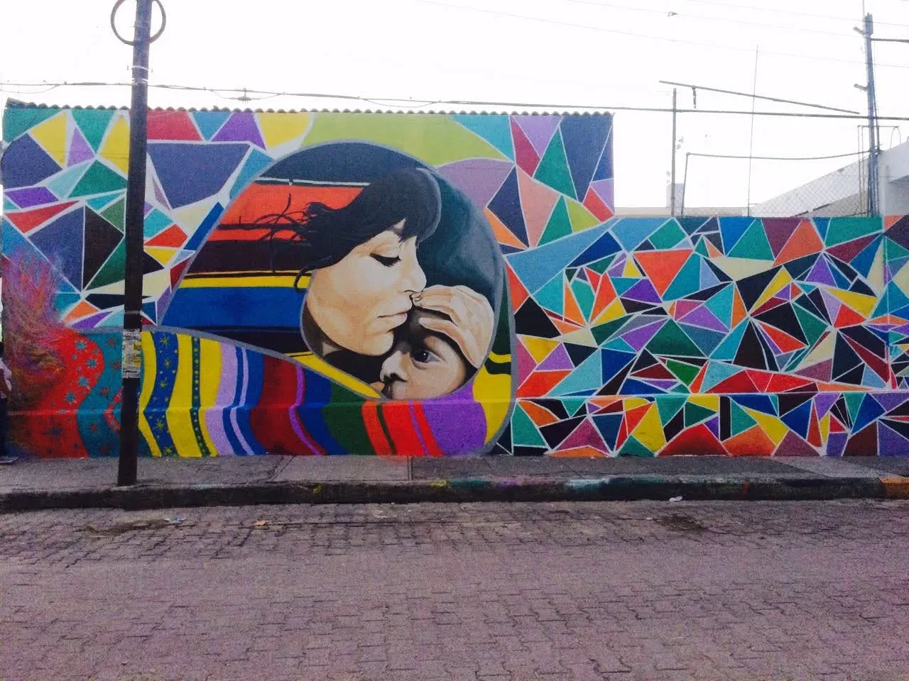 Mural geométrico de colores con el rostro de dos personas abrazándose