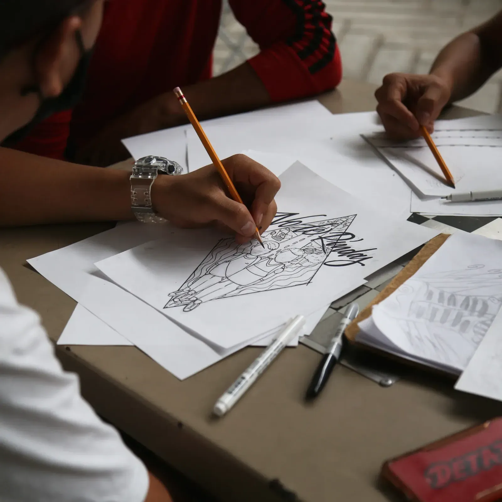 Manos dibujan a lápiz un diseño sobre papel durante el taller